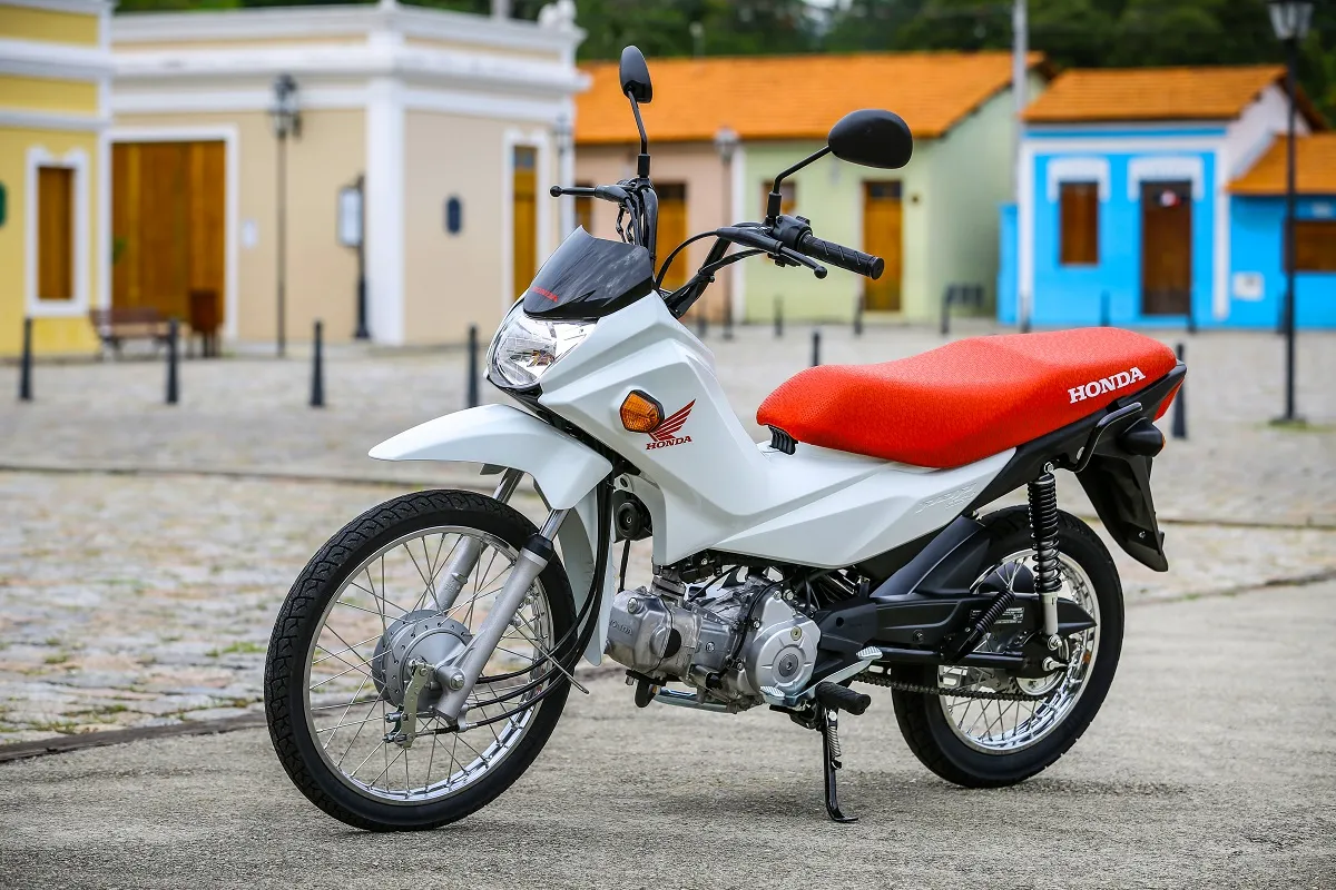 Moto Honda Pop 110i Branca com Banco Vermelho e Casas ao Fundo