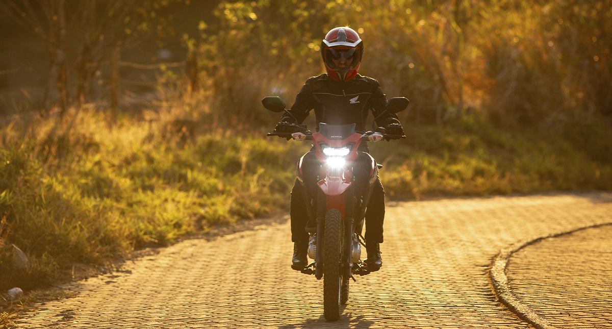 Piloto na moto Honda NXR Bros 160 em estrada de ladrilhos