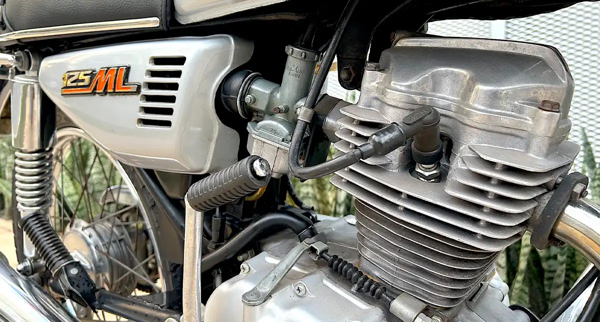 Detalhe do motor da Moto Honda 125 ML, mostrando o logo e os componentes	Detalhe do Motor da motocicleta Honda 125 ML
